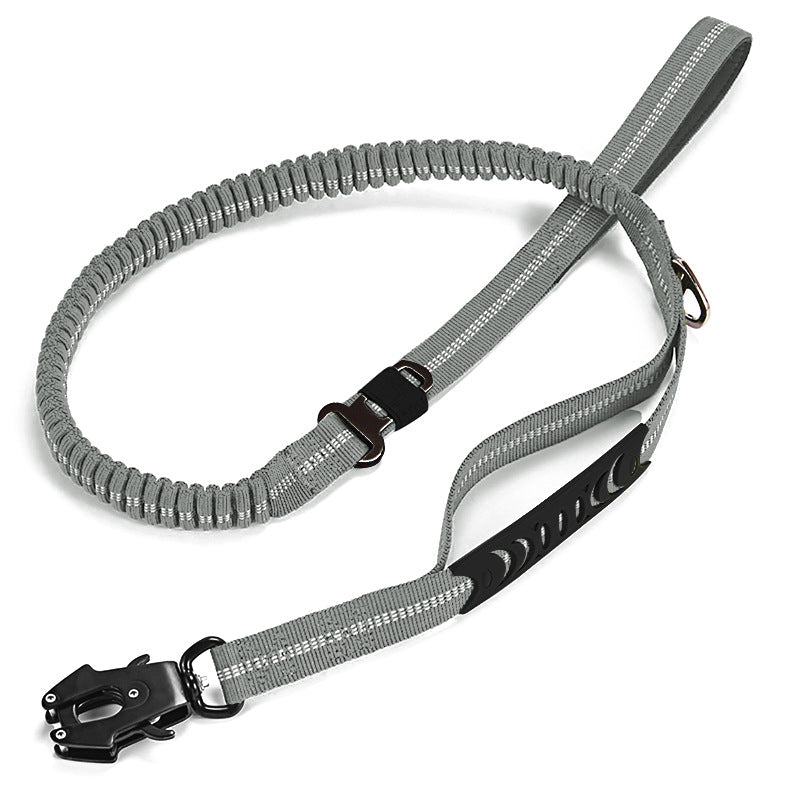 Et produktbillede af en lysegrå, elastisk hundesnor. Snoren har et flettet chok-afsnit, hvide reflekterende striber, en D-ring, et polstret håndtag, et sekundært sort gummihåndtag, og en sort karabinhage i militærstil.