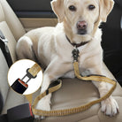 En lys Labrador Retriever sidder på et brunt lædersæde i en bil. Hunden er sikret med en gul-beige, elastisk sele, der er fastgjort til dens halsbånd og klikket i bilens sikkerhedsselespænde, hvilket vises i et forstørret cirkulært indsat billede.