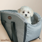 En nuttet hvid Malteser-hvalp sidder komfortabelt og sikkert i et gråt Snudles luksus hunde bilsæde på passagersædet, klar til en biltur.