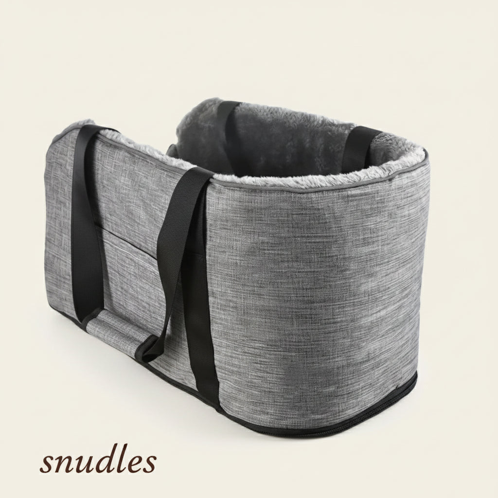 Et gråt Snudles sikkerhedssæde til hunde, set fra en højere vinkel, med robuste stropper på ydersiden og et blødt, behageligt for, ideelt til sikker transport af kæledyr, fotograferet på en hvid baggrund.