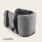 Et gråt Snudles sikkerhedssæde til hunde, set fra en højere vinkel, med robuste stropper på ydersiden og et blødt, behageligt for, ideelt til sikker transport af kæledyr, fotograferet på en hvid baggrund.